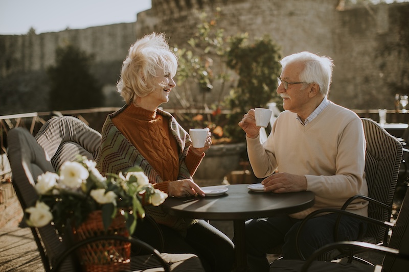 Äldre par i solen som dricker kaffe